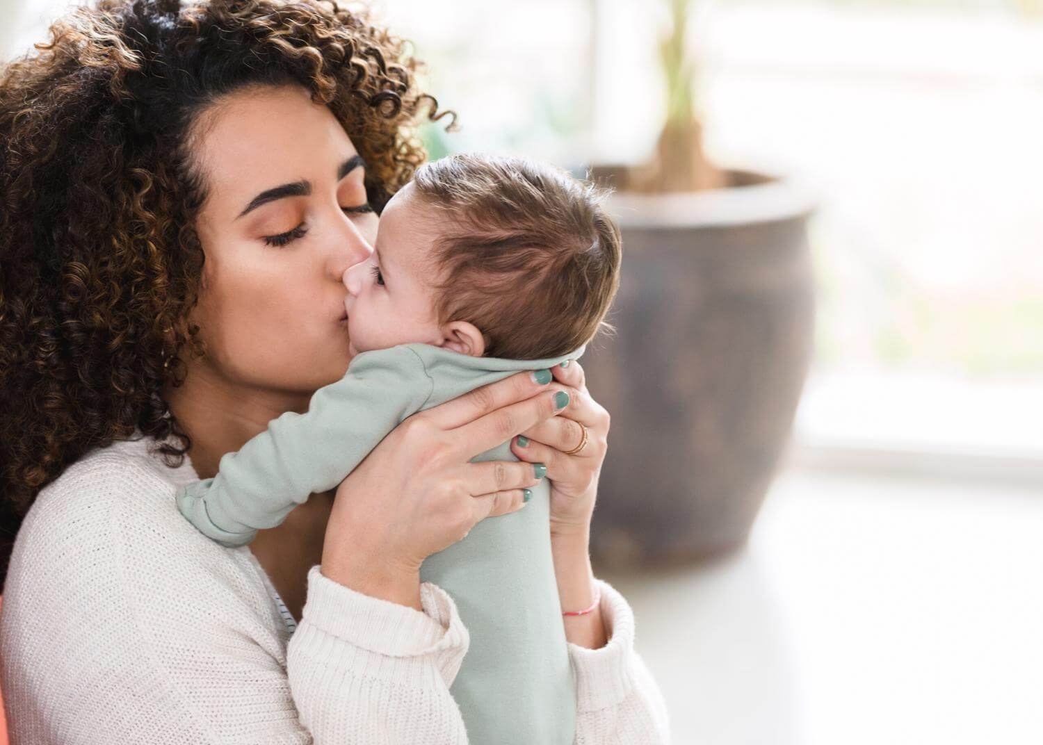 Woman holding baby close and kissing their cheek